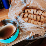RawFedK9 medallions displayed in an open product box with an empty dog bowl beside it, highlighting convenient raw feeding with balanced, portioned meals ready to serve.