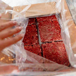 RawFedK9 PMR patties inside an open product box, highlighting balanced raw dog food made from muscle meat, bone, and organ in convenient packaging.