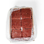 Overhead view of an open RawFedK9 PMR patties product box, showing neatly packaged balanced raw meals made with muscle meat, bone, and organ.