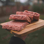 RawFedK9 PMR patties arranged on a cutting board, showcasing balanced, biologically appropriate raw meals made from muscle meat, bone, and organ.