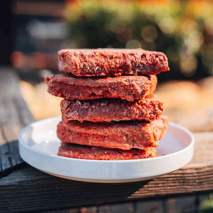 Stack of RawFedK9 raw patties on a plate, highlighting the fresh, high-quality appearance of biologically appropriate raw dog food.