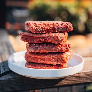 Stack of RawFedK9 raw patties on a plate, highlighting the fresh, high-quality appearance of biologically appropriate raw dog food.