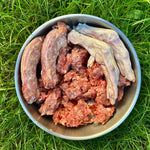 Bowl filled with RawFedK9 PMR patties, raw chicken neck, and raw duck feet, highlighting a balanced, biologically appropriate raw meal for dogs.
