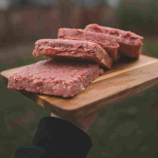 RawFedK9 PMR patties arranged on a cutting board, showcasing balanced, biologically appropriate raw meals made from muscle meat, bone, and organ.